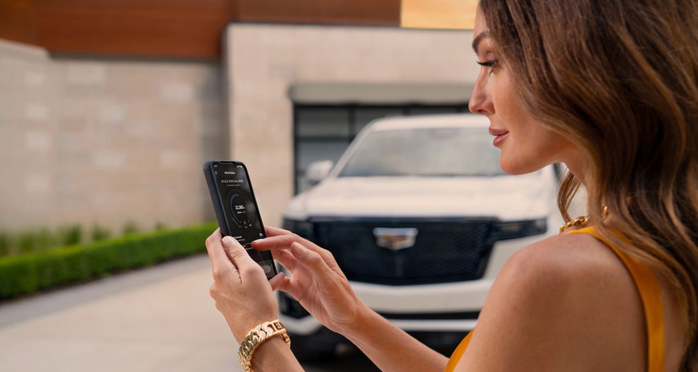 lady checking her mobile with a Cadillac vehicle background | Rick Bokman Cadillac in OLEAN NY